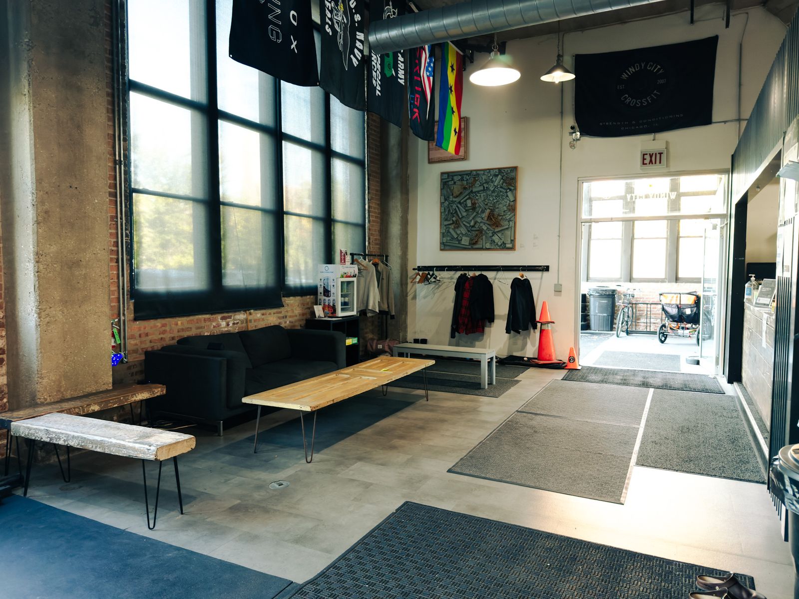 The front lounge just inside the gym entrance, with a couch, benches and big warehouse windows